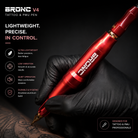 Red tattoo pen held in a black glove with promotional text on a dark background
